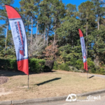 Feather flags with "New Homes" displayed along a roadside in a residential area.